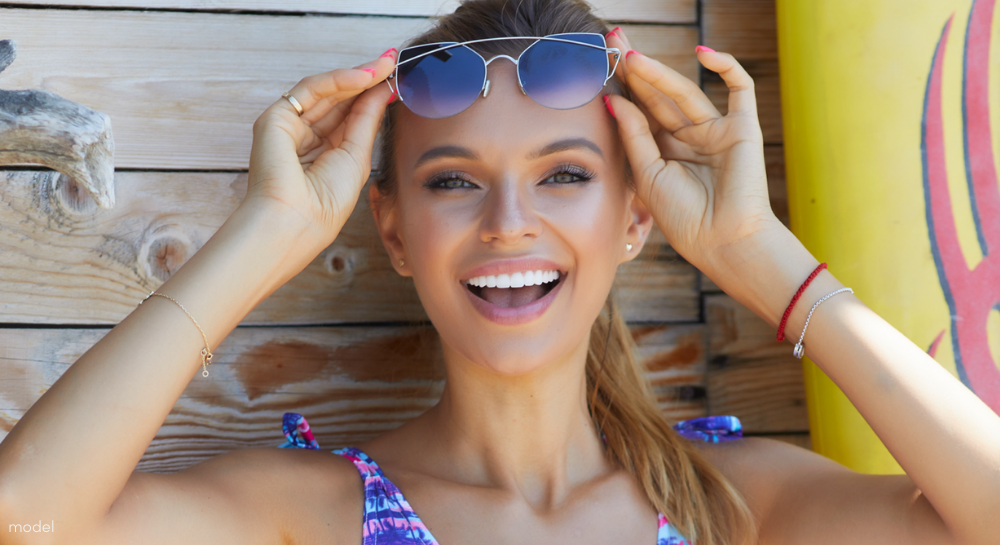 Woman raising her sunglasses above her eyes and smiling