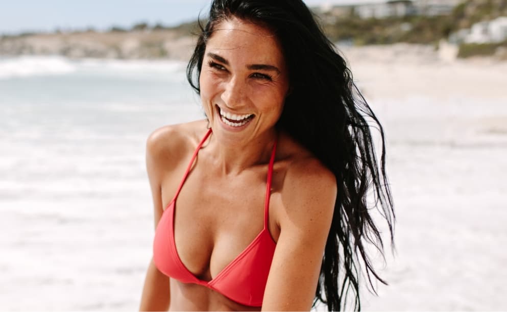 Woman on beach wearing a coral bikini