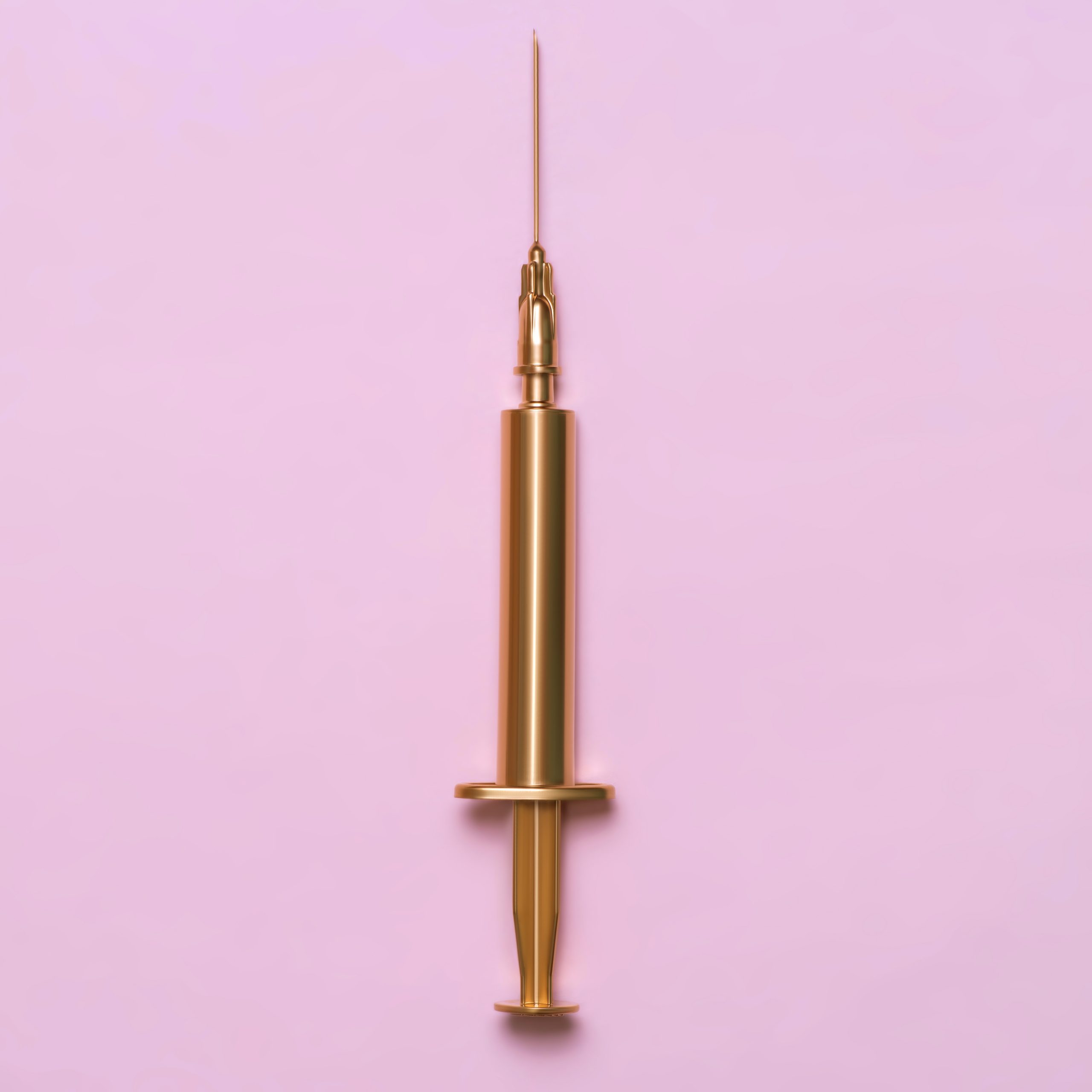 Golden syringe on a pink background