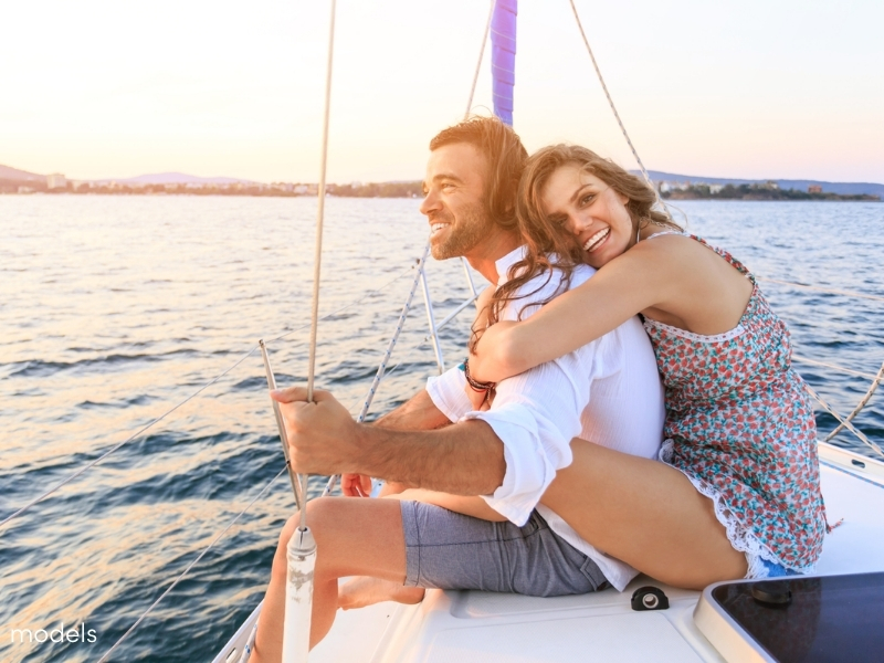 young couple smiling on a boat during golden hour