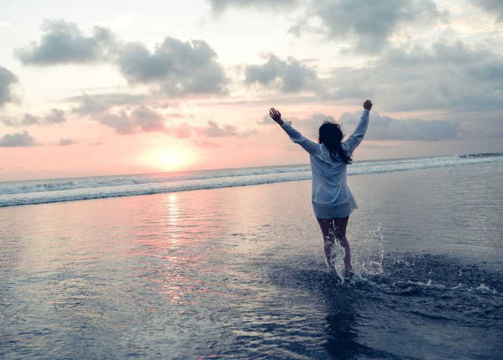 Woman strikes a confident and joyful pose on the beach