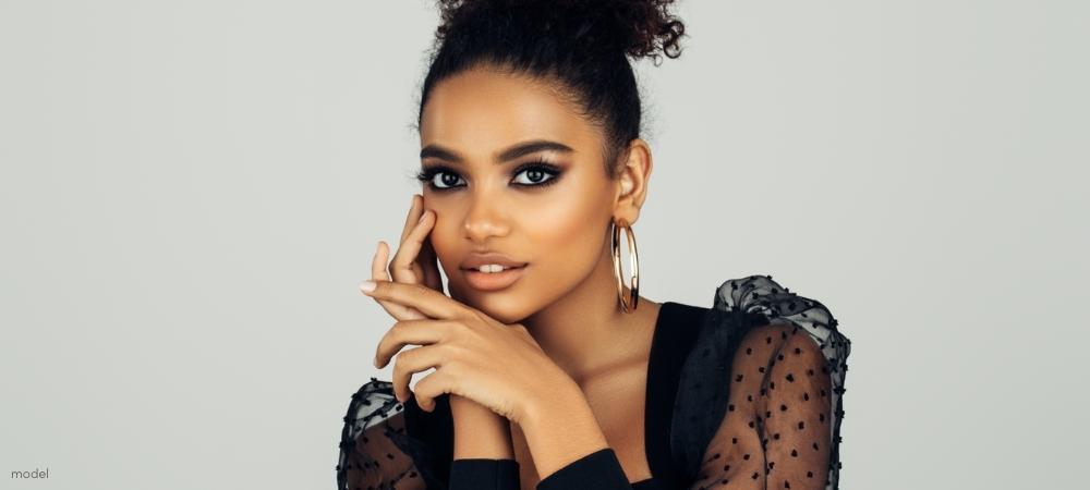 Beautiful African-American woman wearing Black fancy blouse resting hands on chin