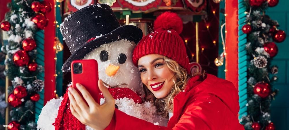 Beautiful woman taking a selfie with a snowman