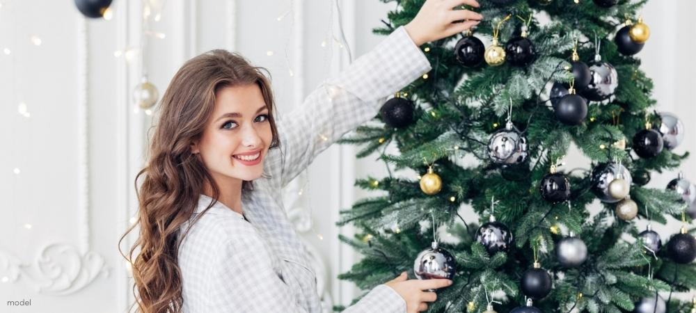 Woman in her pajamas on Christmas Morning standing by the Christmas tree