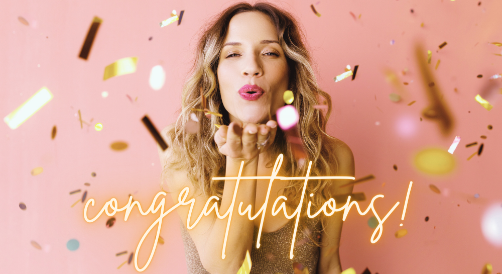 Brunette woman blowing confetti at the camera. [congratulations!]