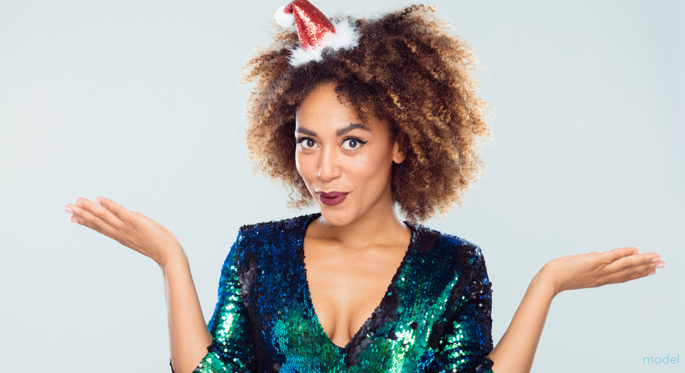 Portrait of happy young woman wearing green sequined dress and santa hat on white background.
