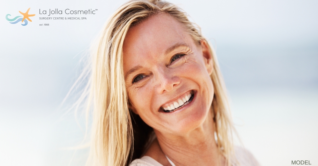 blonde woman in her late sixties smiling on a sunny day at the beach (model)