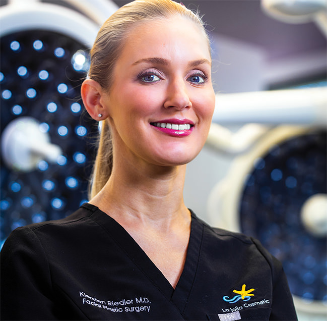 Dr. Kiersten Riedler, facial plastic surgeon at LJCSC – La Jolla Cosmetic Surgery Centre – confidently standing in a state-of-the-art surgical suite.