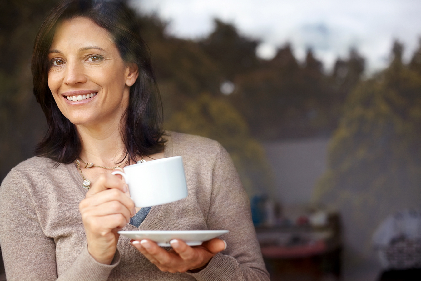 Woman in her 30s or 40s, possibly a mom, looking curious with cup of coffee. Do you have to be a mom to have a mommy makeover? Woman looking inquisitive as she drinks coffee.
