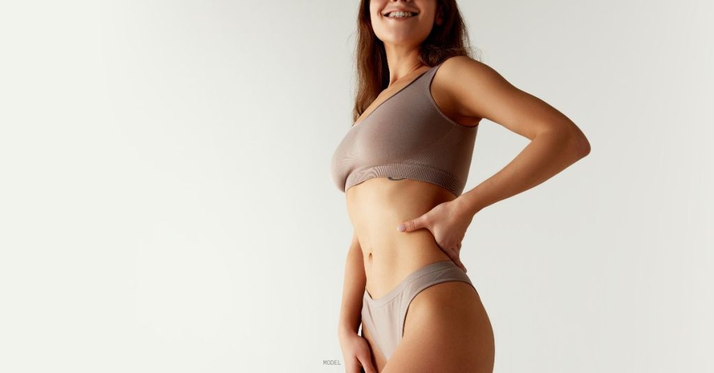 woman standing and showing off her liposuctions results (model)