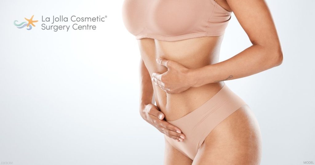 Woman holding their stomach after a tummy tuck surgery. (Model)