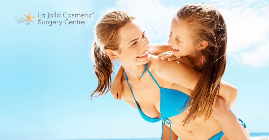 Woman after a mommy makeover with her daughter at the beach. (Model)