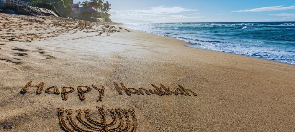 “Happy Hanukkah” written in the sand