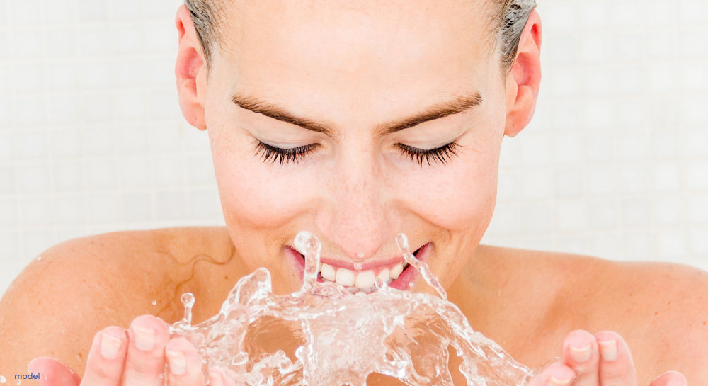 close up of woman splashing water on her face